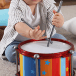 A child playing a drum while singing BIble songs.