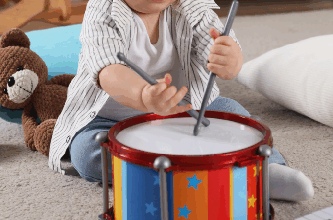 A child playing a drum while singing BIble songs.