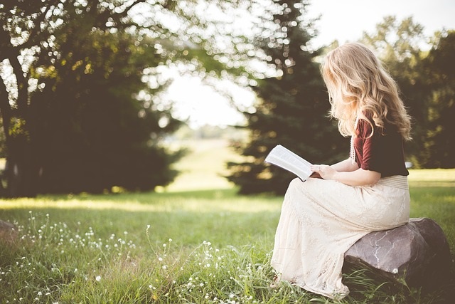 Woman sitting on a rock reading her Bible for Quiet Time.