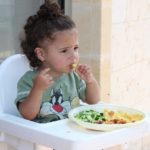 Child eating food in the highchair.