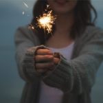 A woman holding a sparkler fire cracker.