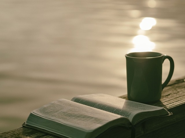 Bible and cup of coffee looking over a sunrise.