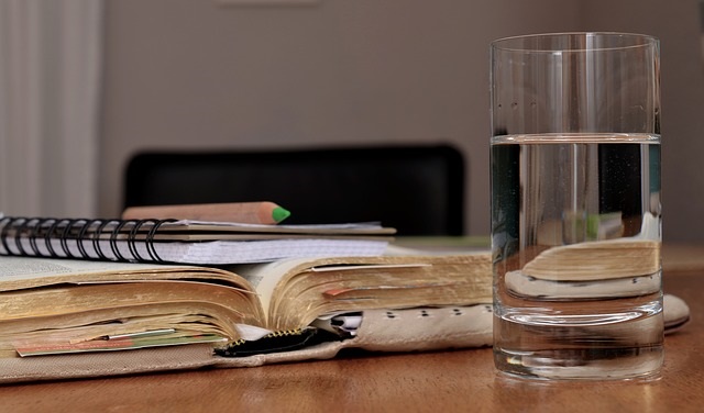 Bible, notebook, and pencil with a glass of water prepared for a Quiet Time.