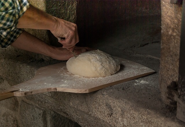 Woman cutting a loaf of bread dough.