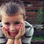 A boy sitting with hands on his chin.