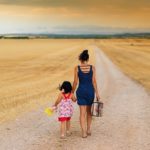 Mom and child walking down gravel road.