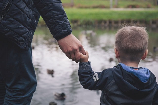 Young boy holding hands with adults