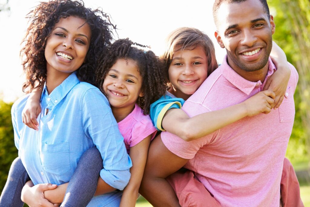 Family with two children riding on parents' backs.