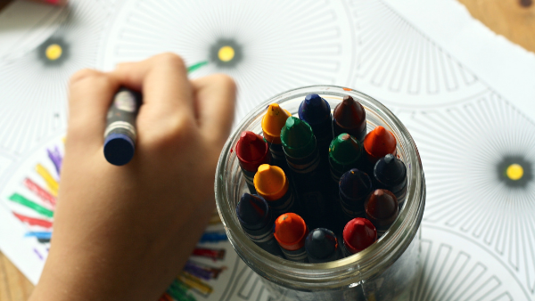 Child coloring with crayons in kindergarten.