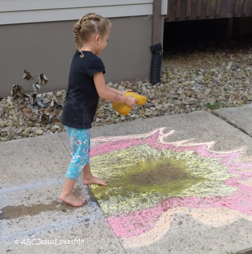 Child playing with water and sidewalk chalk.