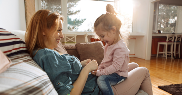 Child sitting on her mom's lap.  They are holding hands.