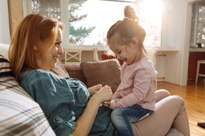 Child sitting on her mom's lap. They are holding hands.