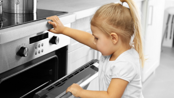 Child checking oven for baked goods.