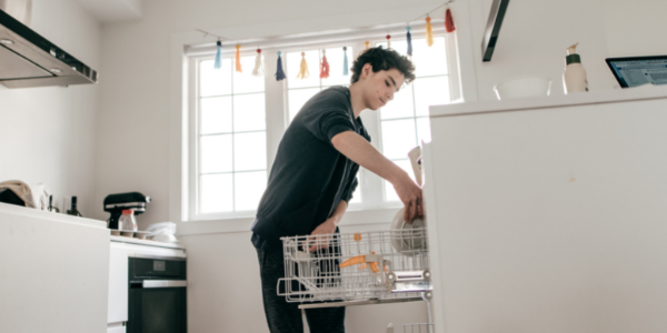 Teen loading the dishwasher.