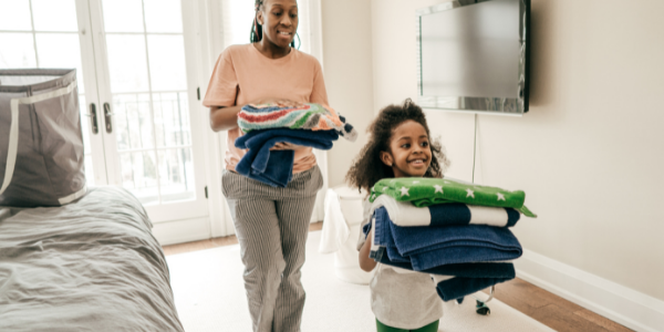 Child putting laundry away with parent.