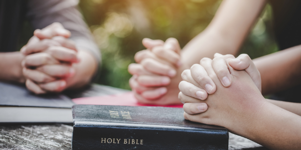 Adults folding hands and praying.