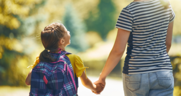 A daughter going to school, holding hands with her mom.