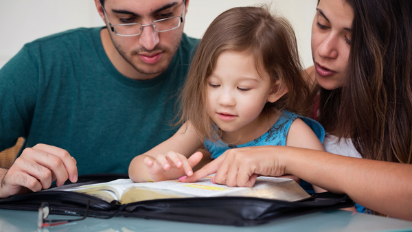 Child reading the Bible with her parents.
