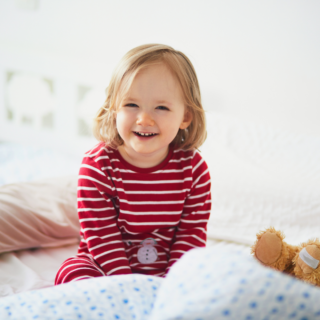 Little girl sitting on her bed.