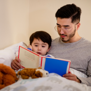 Child and dad reading a book before bed.