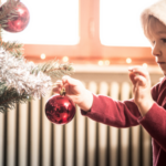 Child putting ornaments on a tree.