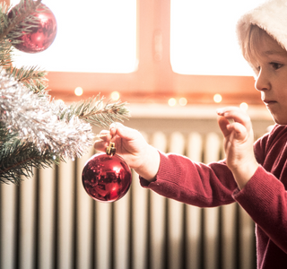 Child putting ornaments on a tree.