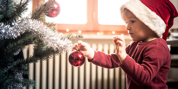 Happy child putting ornaments on a tree.