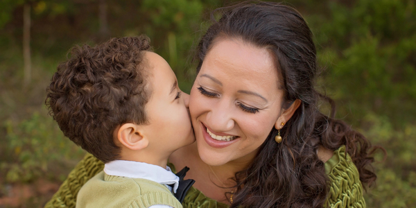 Mom getting a kiss on the check by her son.