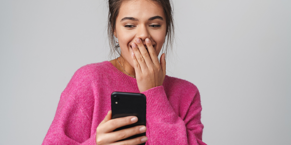 Woman overcoming loneliness by looking at phone and smiling.