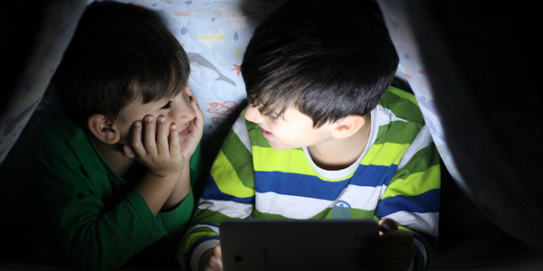 Two boys with screen technology under tent.