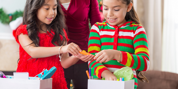 Two girls filling a Christmas box.