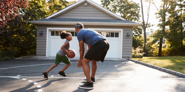A dad and daughter playing basketball.