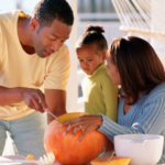 Mom and Dad carving a pumpkin with child.