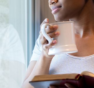 Woman holding her Bible and coffee while reflecting.