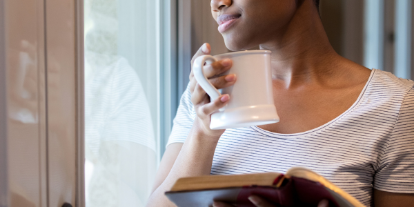 Woman holding her Bible and coffee while reflecting.