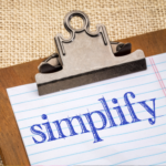 Clipboard with a paper saying, "Simplify"