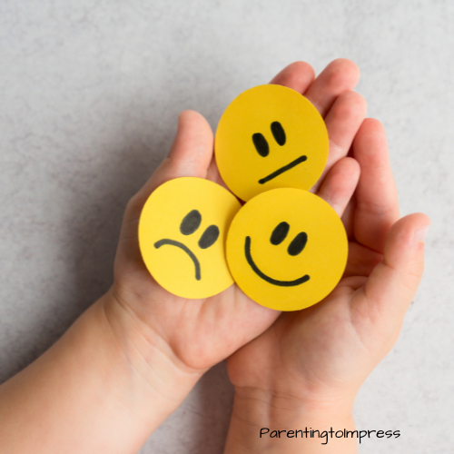 A child's hands holding paper emojis.