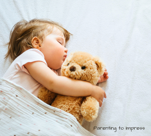 Child sleeping while holding a teddy bear.