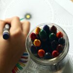 a jar of crayons, and a child coloring