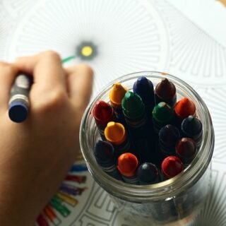 a jar of crayons, and a child coloring
