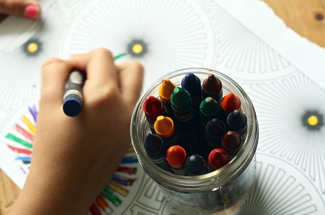 a jar of crayons, and a child coloring