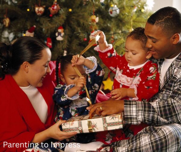2 parents & 2 children in front of a Christmas tree, smiling, opening gifts
