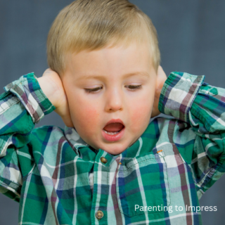 A young boy covering his ears.