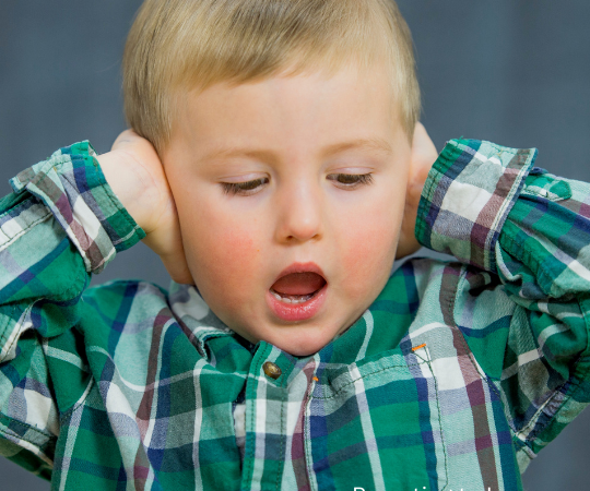 A young boy covering his ears.