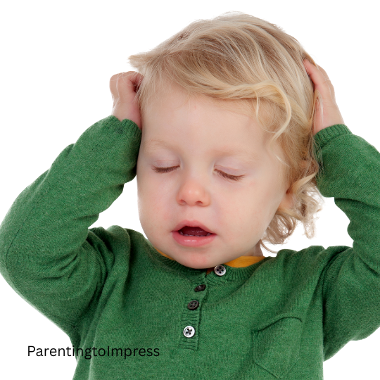 A toddler who is frustrated, hands on his head.