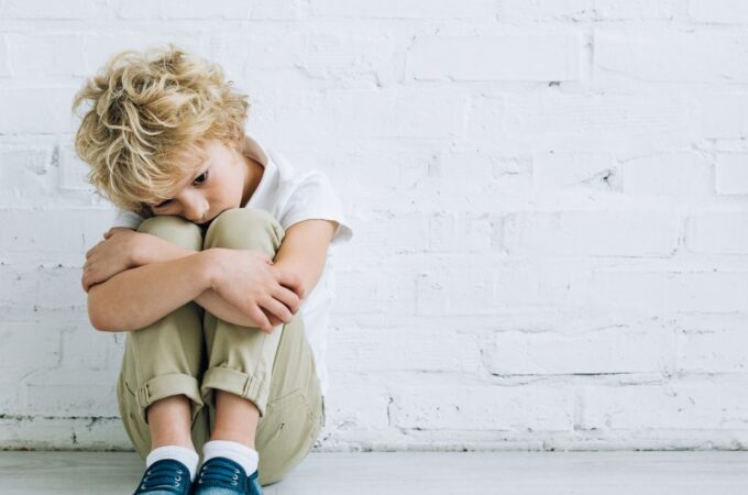 A young boy upset, sitting on the ground.