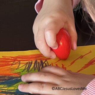 Child coloring with an egg crayon.
