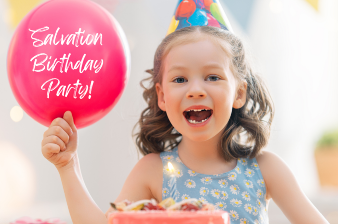 A little girl wearing a birthday hat, next to a birthday cake, holding a balloon that says "Salvation Birthday Party"