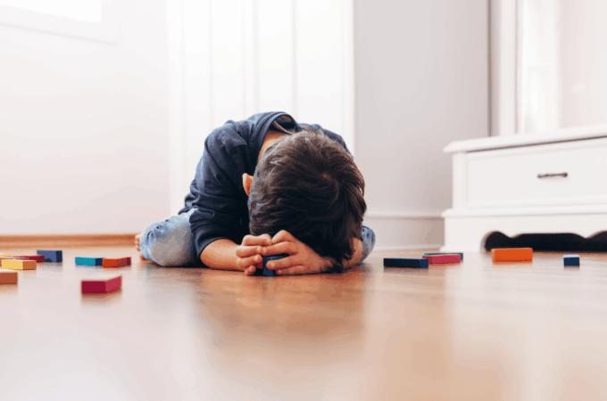 A tired child, lying on the floor with blocks.